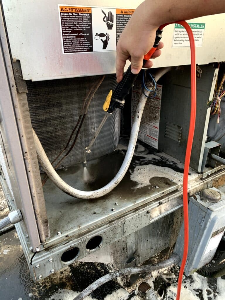 Service Emperor technician cleaning the HVAC coils with chemical cleaner.