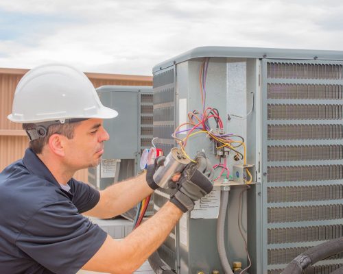 85556380 - hvac technician checking capacitor on air conditioner